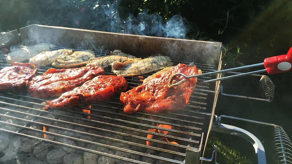 Meat cooking on a charcoal grill over glowing embers