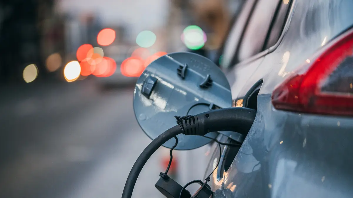 Charging connector plugged into an electric car on the street