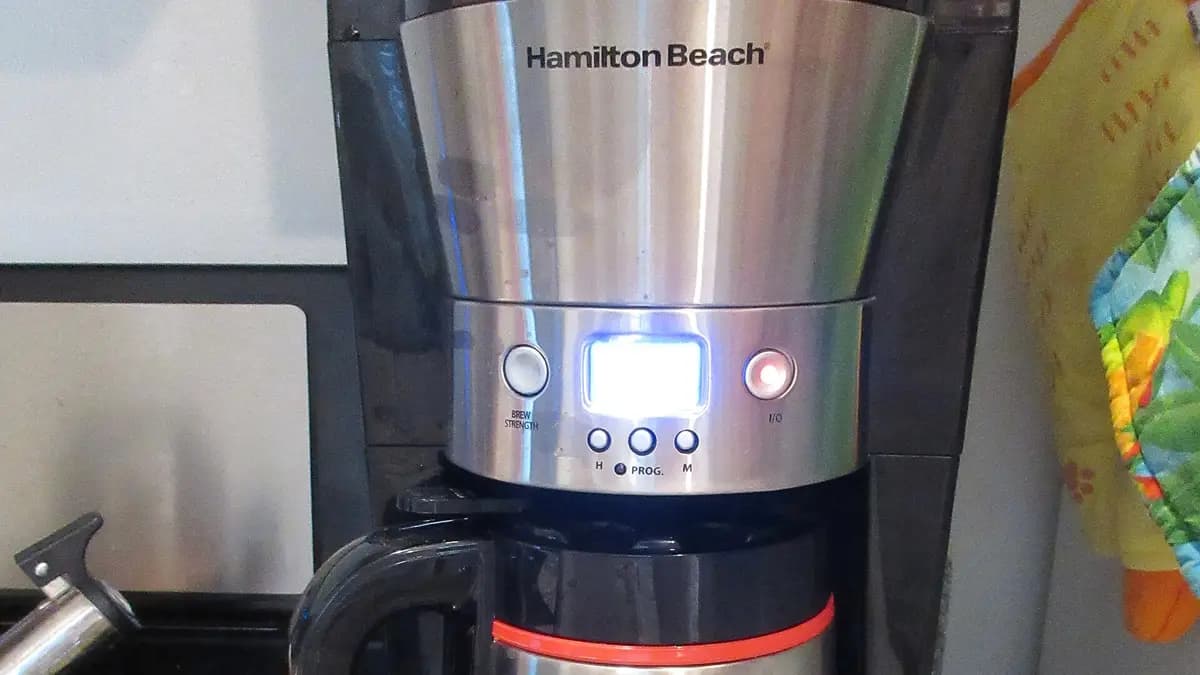 Stainless steel drip coffee maker with a jug on a kitchen counter