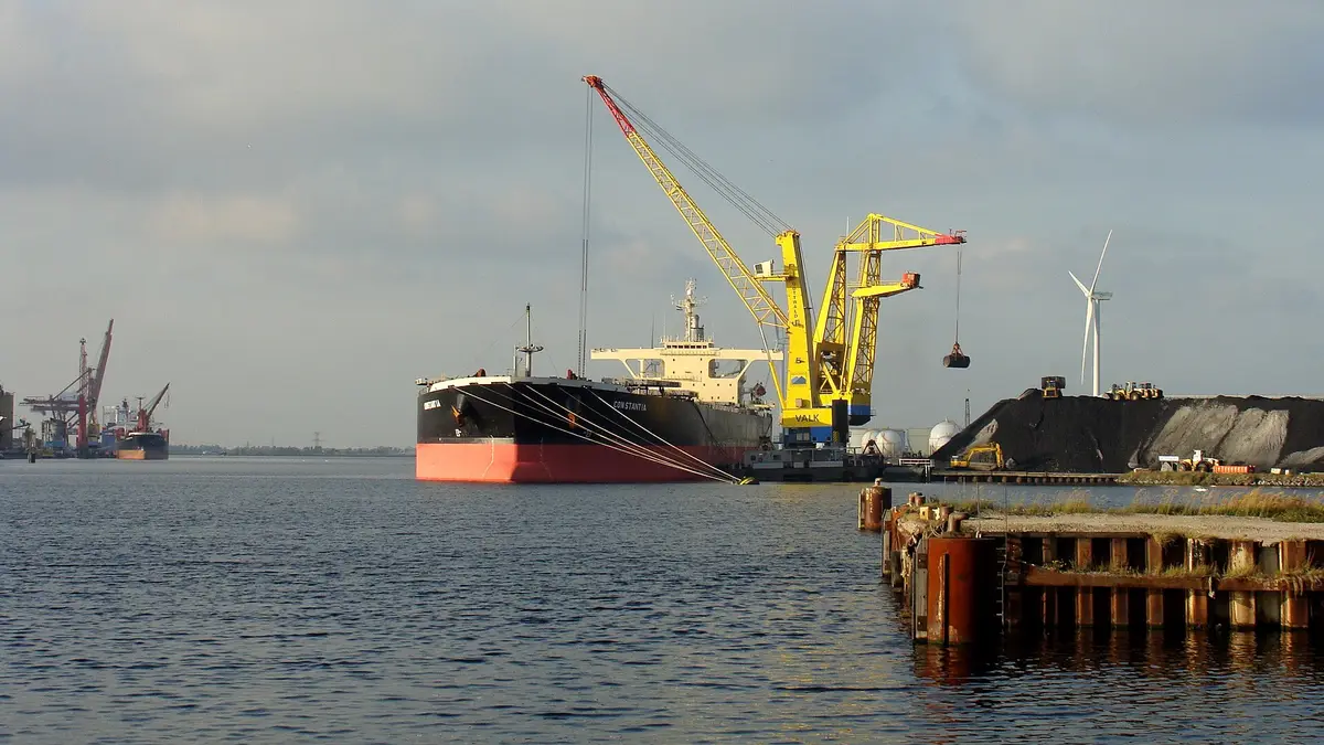 Crane unloading coal from a bulk carrier to a stockpile in a port