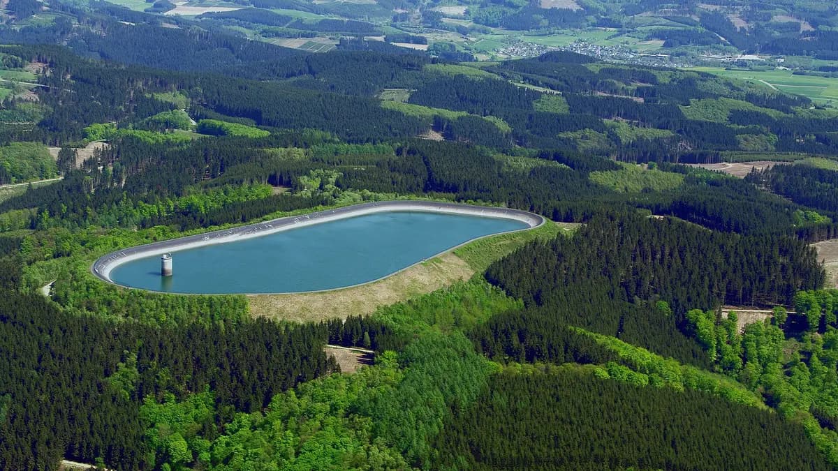 Oval upper reservoir of a pumped storage hydropower plant surrounded by forest in Germany