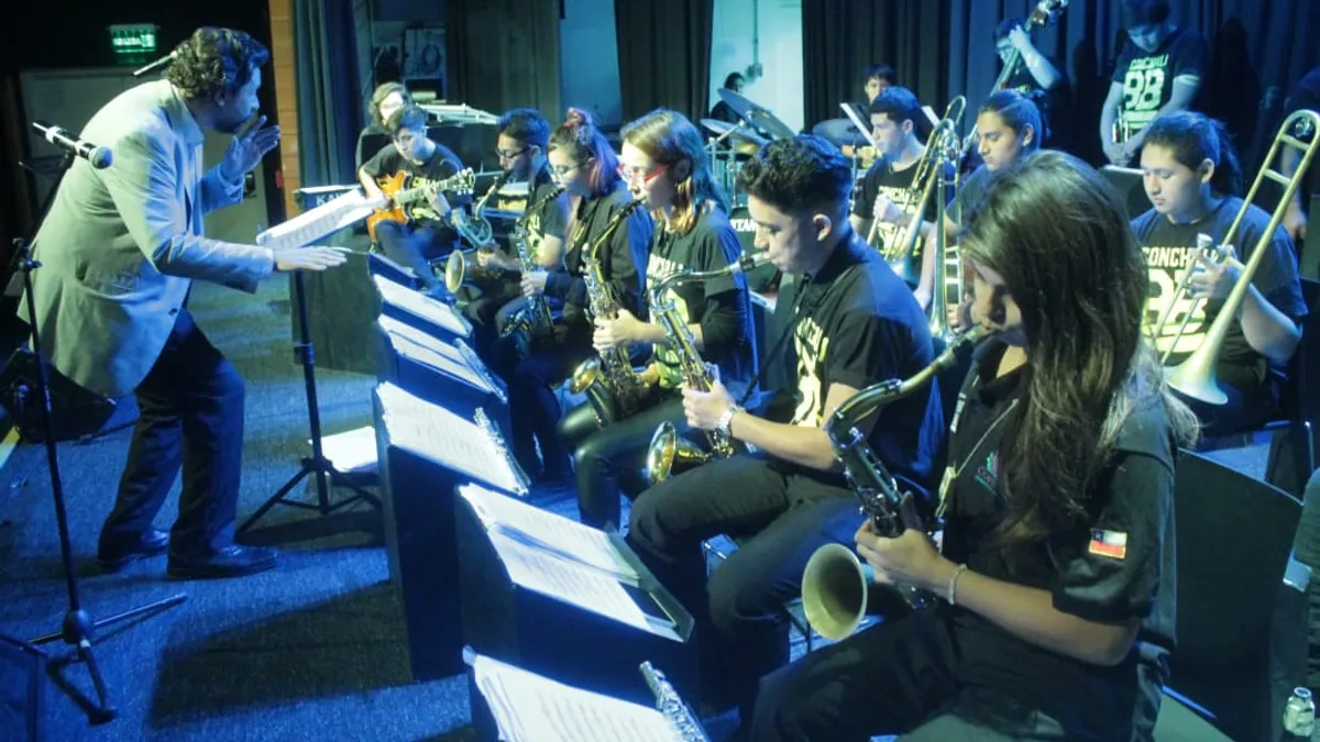 Músicos jóvenes de la Conchalí Big Band tocando saxofones y trombones en un escenario