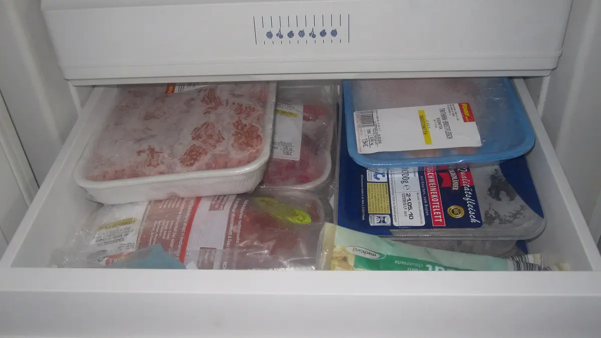 Cajón de congelador abierto con carnes y alimentos envasados
