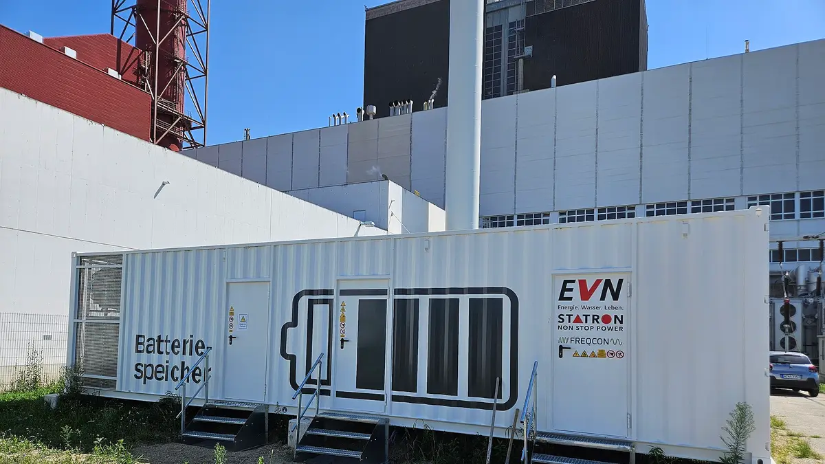 White container of a battery energy storage system next to a power plant