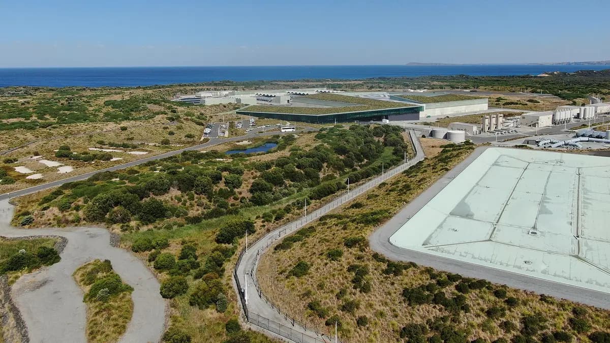 Aerial view of a desalination plant by the sea, with storage pools and a green roof surrounded by vegetation