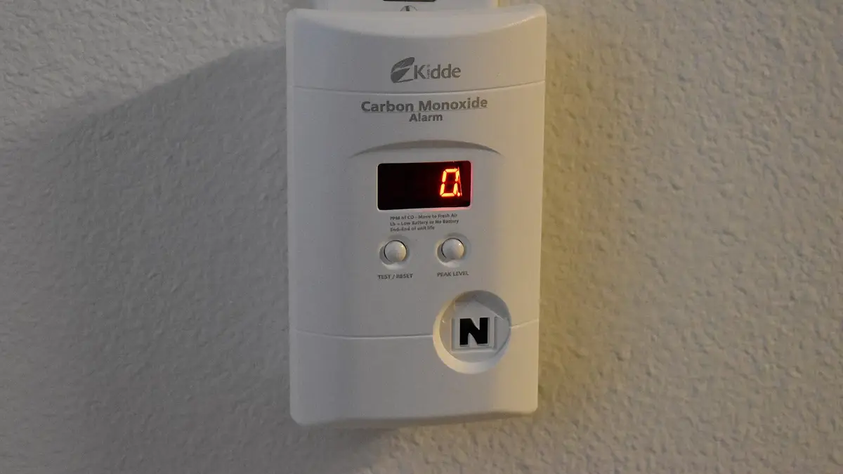 Carbon monoxide detector mounted on a wall, with a digital display reading zero