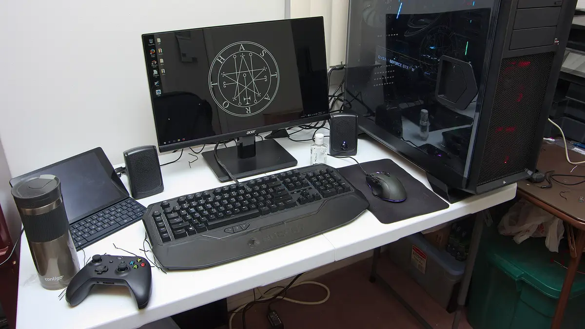 Escritorio con un computador gamer de torre, monitor, teclado, mouse, parlantes y un control de videojuegos