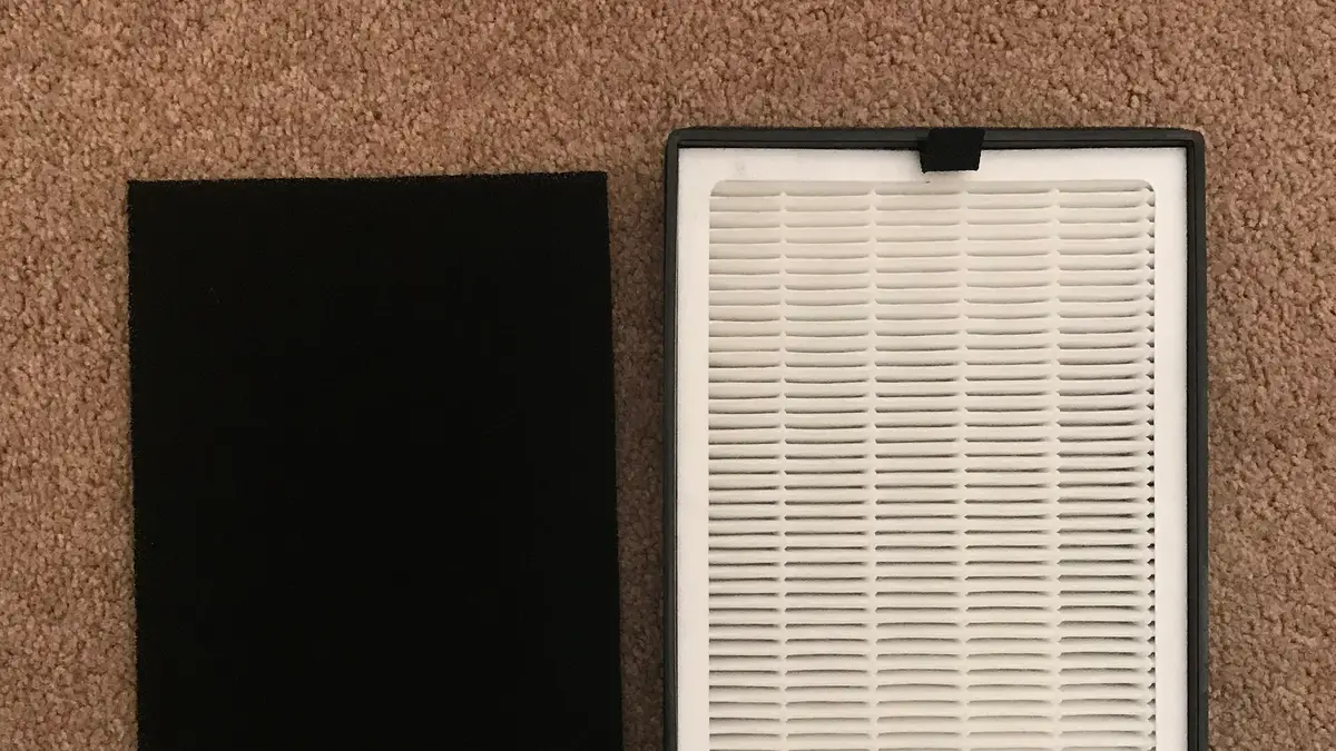 Filtro HEPA branco plissado ao lado de um filtro de carvão ativado preto de um purificador de ar