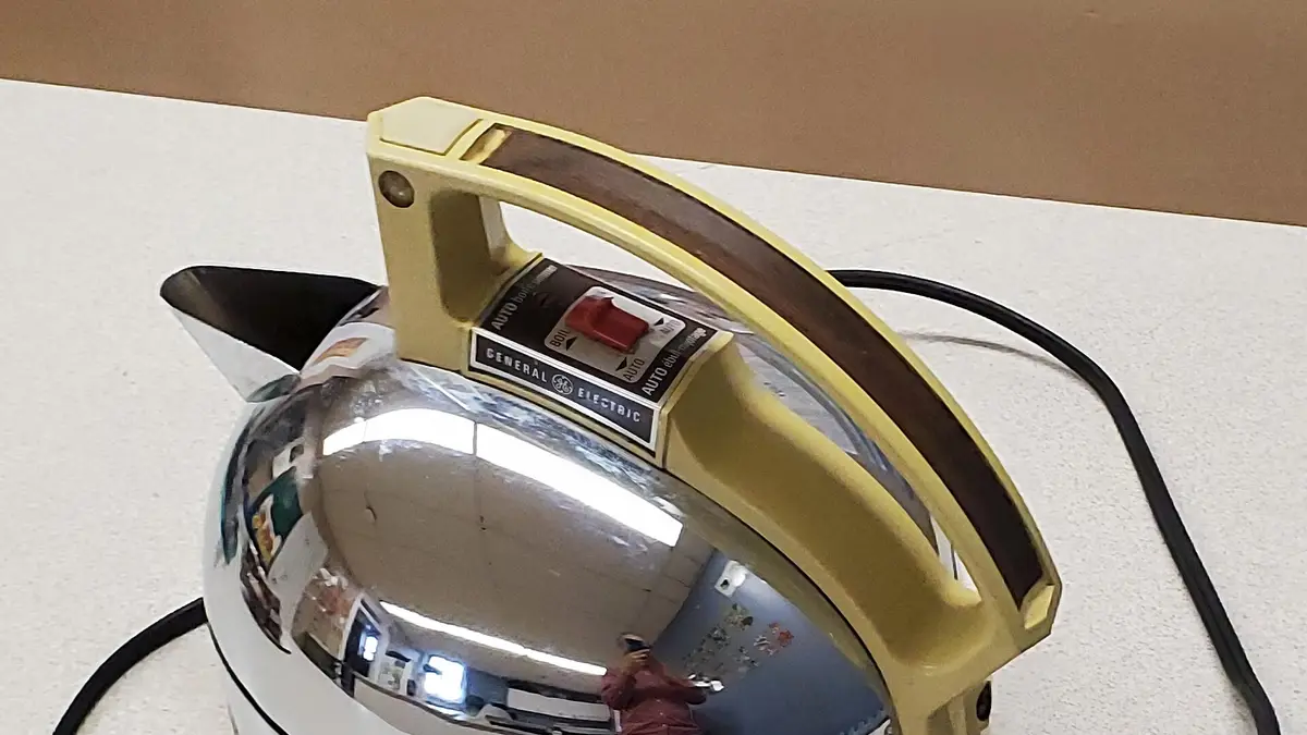 Hervidor eléctrico antiguo de acero cromado con mango