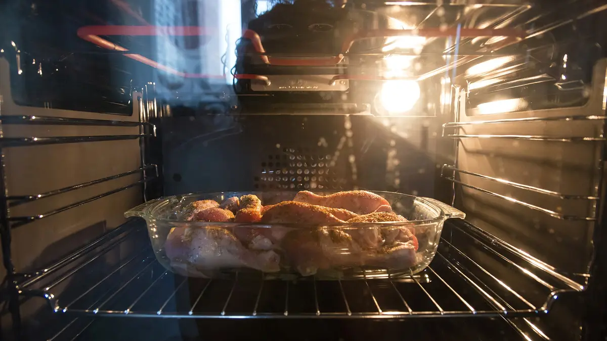 Frango assado dentro de um forno elétrico com a luz acesa