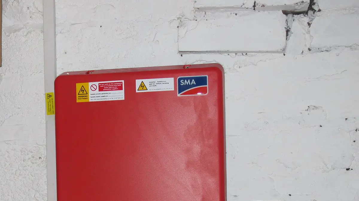 Red solar inverter mounted on a white wall