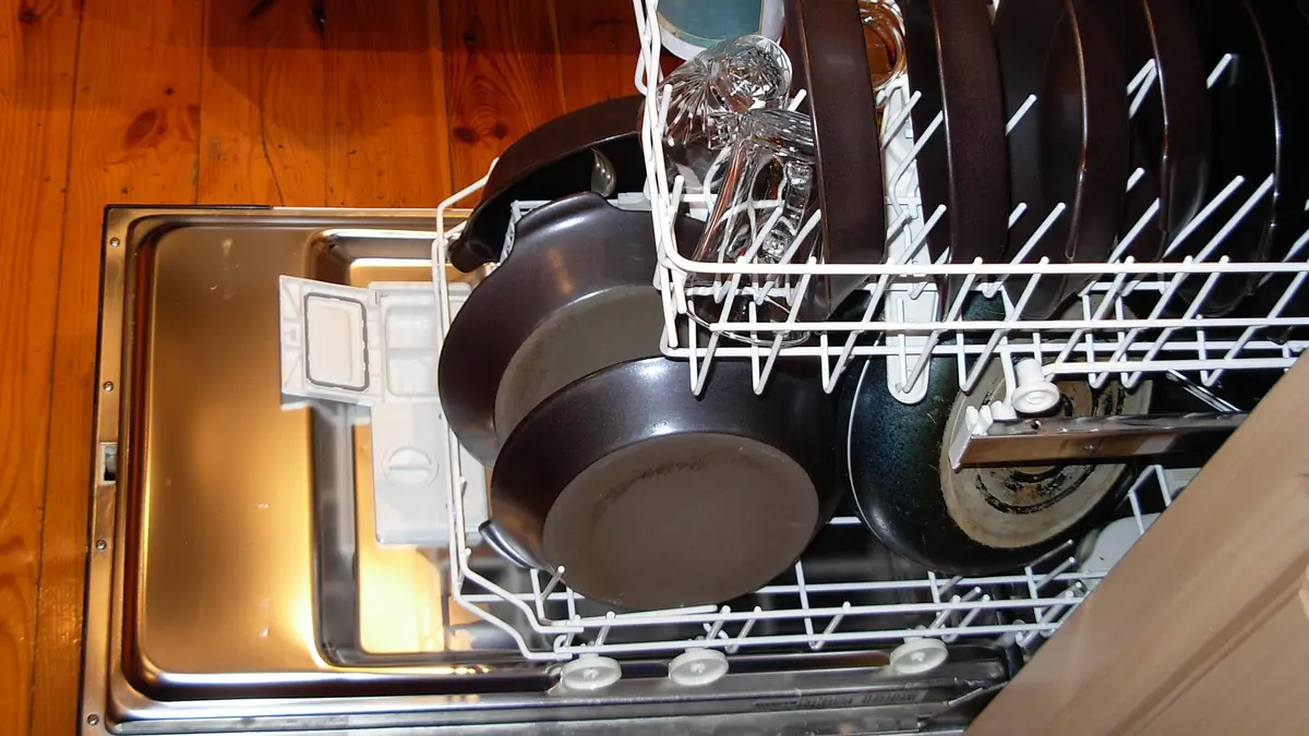 Lavavajillas abierto con ollas y platos en la bandeja inferior