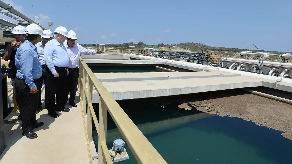 Visitantes com capacetes brancos percorrem os tanques de pré-tratamento da usina de dessalinização de Sorek, em Israel