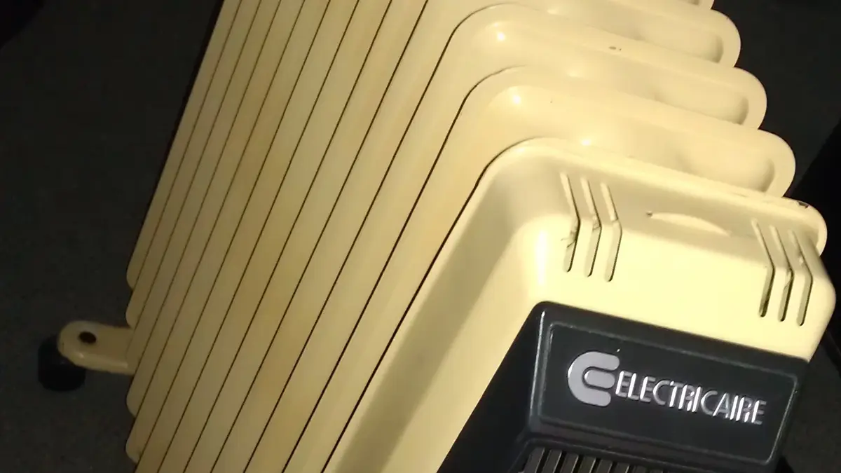 Cream-colored electric oil radiator plugged in in a room