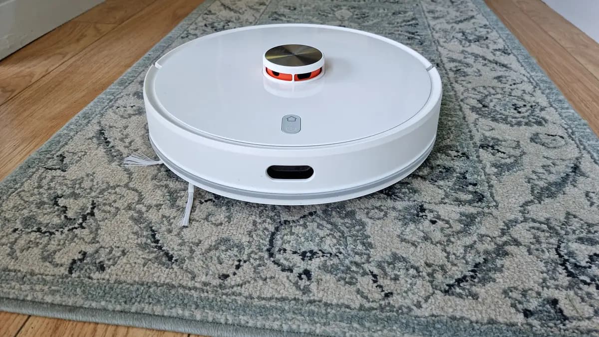 White robot vacuum with a laser sensor on a rug