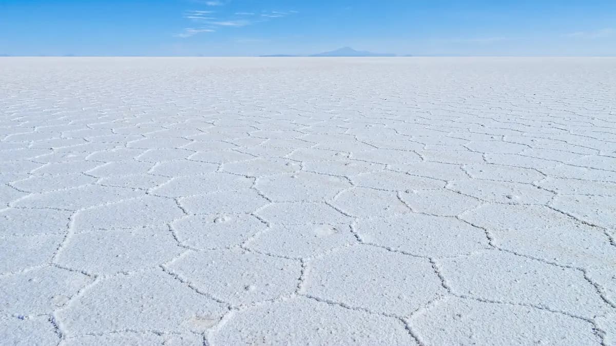 White, cracked surface of the Salar de Uyuni in Bolivia under a blue sky