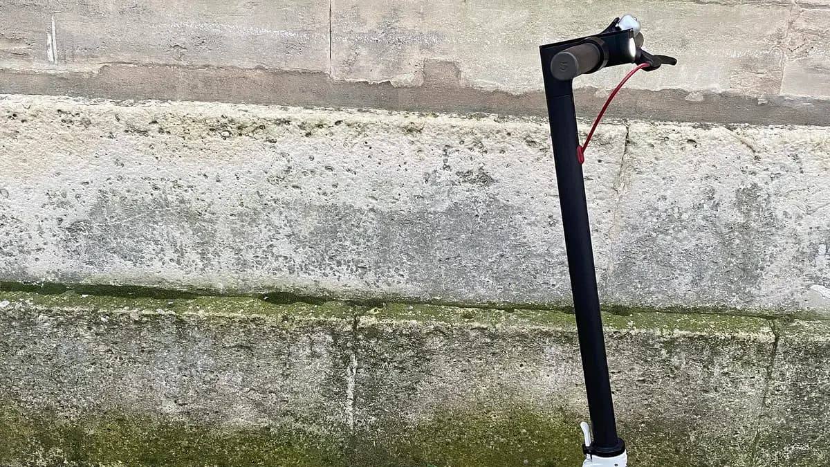 Patinete elétrico Xiaomi M365 branco apoiado em um muro de pedra