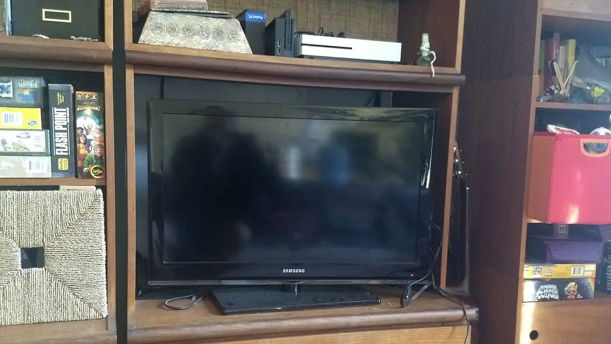 Televisor de tela plana sobre um móvel de madeira com prateleiras