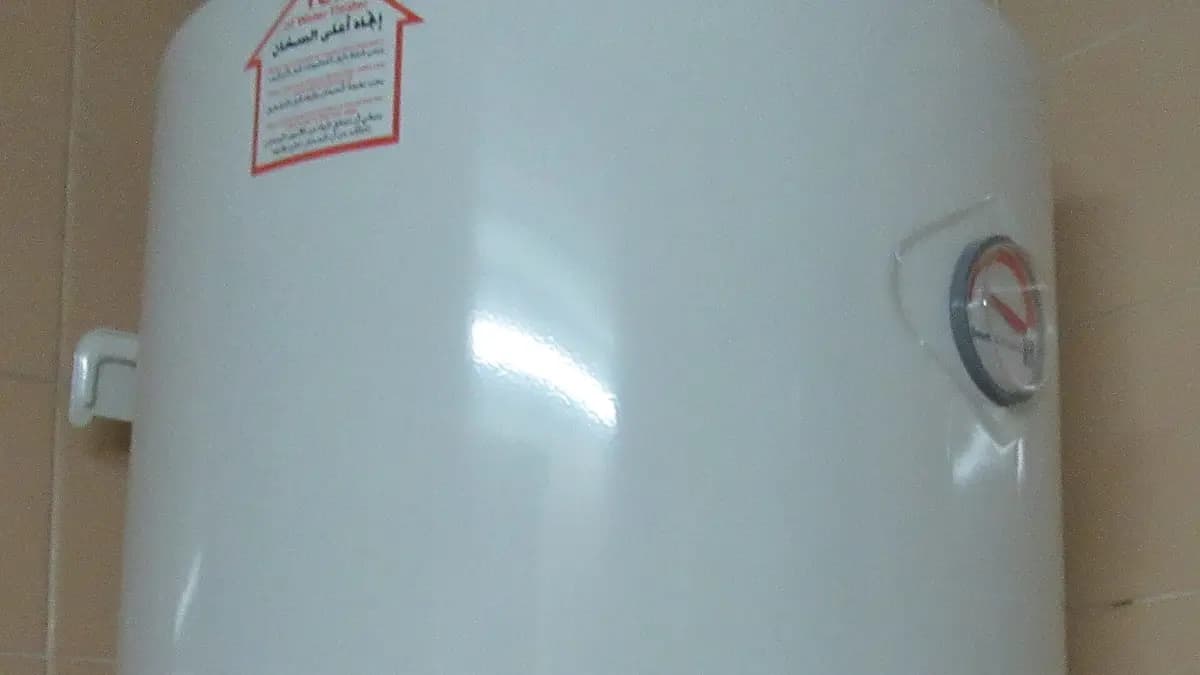 Aquecedor elétrico de água branco instalado na parede com botão de temperatura