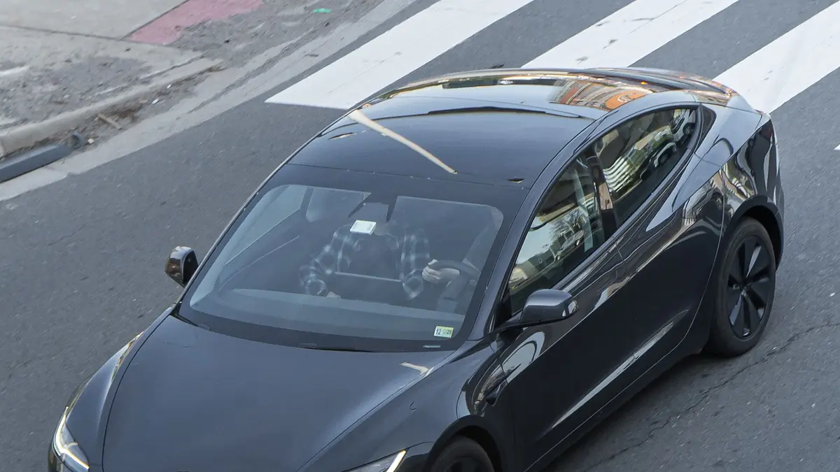 Tesla Model 3 preto estacionado em uma rua visto de cima