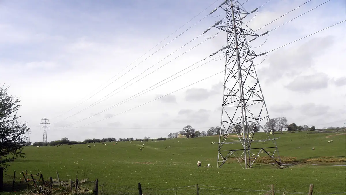 High-voltage pylon with power lines over a green field